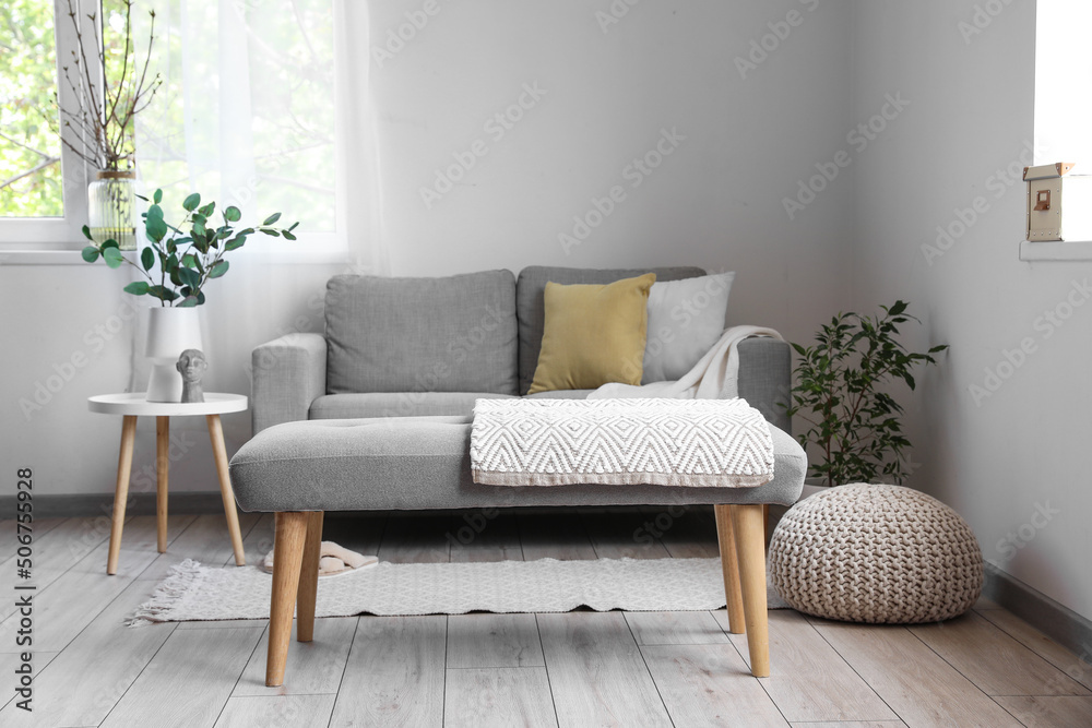 Obraz premium Interior of light living room with soft bench, sofa and houseplants