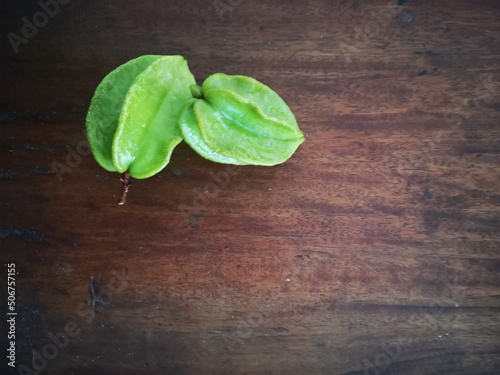 Green carambolas on wooden background 2