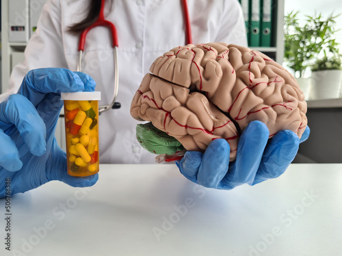 Nocebo effect concept. Female doctor holding brain model and placebo supplement pill photo
