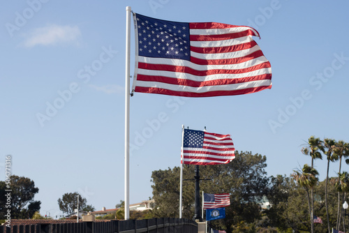 Waving American flags in the wind against blue sky on the Balboa Island Channel Bridge in Newport Beach, California.