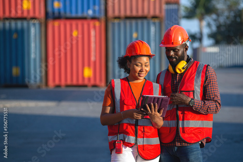 Happy African American female and male worker using tablet during video call in a logistic shipping cargo containers yard.