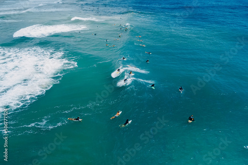 Surfers on surf spot and waves in blue ocean. Aerial view of surfers during surfing