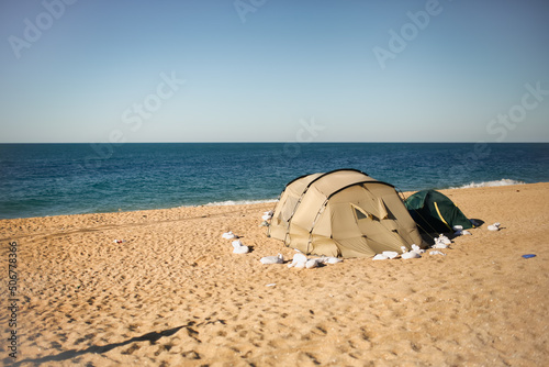 Two camping tents by sea, tents are secured with sacks. sand for safety. Camping by the sea