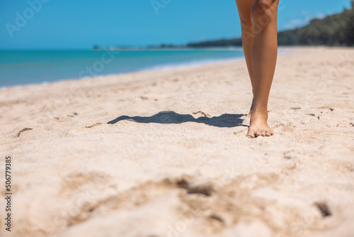 close up Bare foot woman walking on golden sand beach in Khao Lak, Phang Nga, Thailand. Summer vacation concept.