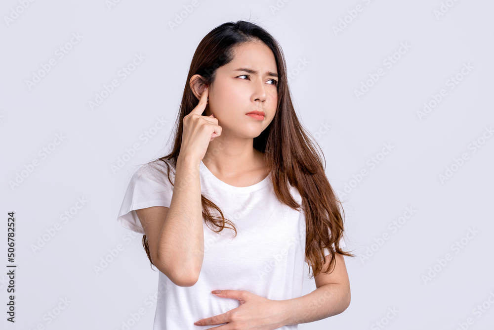 Young asian woman with facial piercing holding finger at her ear. She having painful grimace, frowning, posing isolated on white background Young asian woman with facial piercing holding finger at her ear. She having painful grimace, frowning, posing isolated on white background