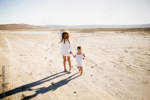 two little sisters walk barefoot in summer run around deserted place in nature, children games and relaxation in the hot summer