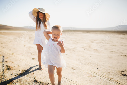 two little sisters walk barefoot in summer run around deserted place in nature, children games and relaxation in the hot summer