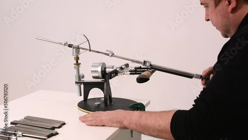 blogger conducts an online master class on sharpening knives on a hand machine.