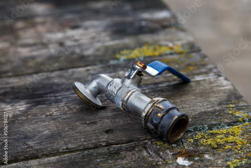 A broken metal water tap on a wooden plank