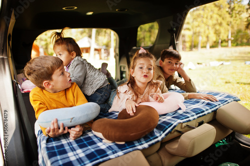 Family of four kids at vehicle interior. Children in trunk. Traveling by car, lying and having fun, atmosphere concept. © AS Photo Family