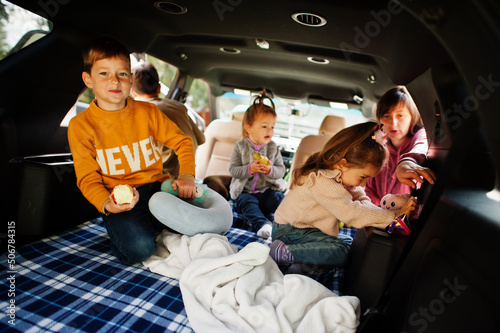 Mother with four kids at vehicle interior. Children in trunk. Traveling by car, lying and having fun, atmosphere concept. © AS Photo Family