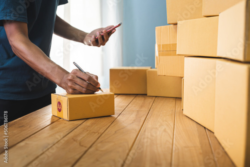 Young entrepreneur business owner work at home, small business startup receive order client and take note working with report and pack the product on purchase delivery online to sending destination.