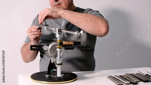 blogger conducts an online master class on sharpening knives on a hand machine.