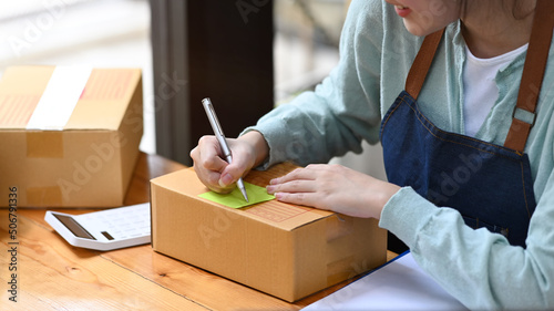 Start up business entrepreneur writing address on cardboard box. Online selling, E-commerce concept