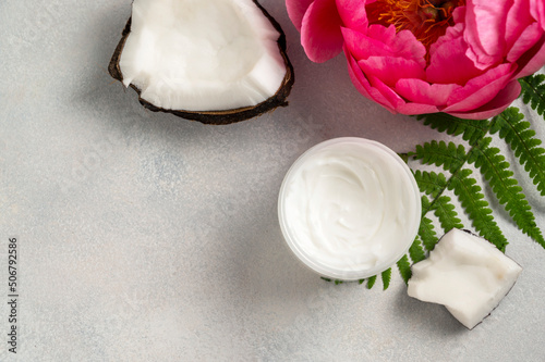 Cosmetic skin care, coconut face cream and pink peony flower on brigt background. photo