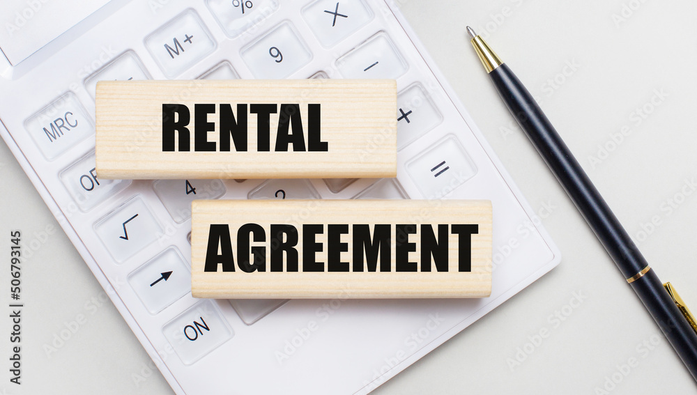 Wooden blocks with the RENTAL AGREEMENT Iie on a light background on a white calculator. Nearby is a black handle. Business concept Wooden blocks with the RENTAL AGREEMENT Iie on a light background on a white calculator. Nearby is a black handle. Business concept