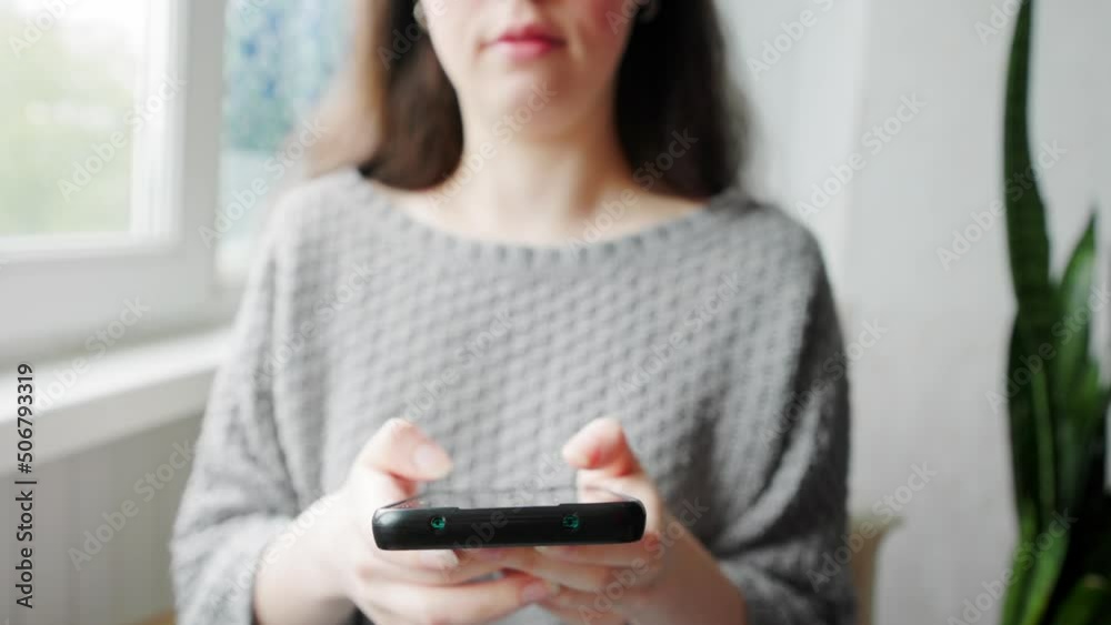A young caucasian woman in home clothes texting at a smartphone. Close up of hands. Social media concept. A young caucasian woman in home clothes texting at a smartphone. Close up of hands. Social media concept.