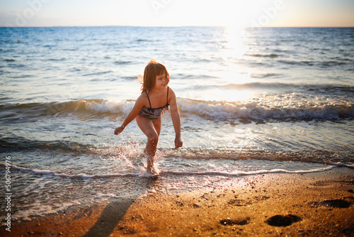 European girl child alone on the seashore, wide angle shooting, vacation with children at sea