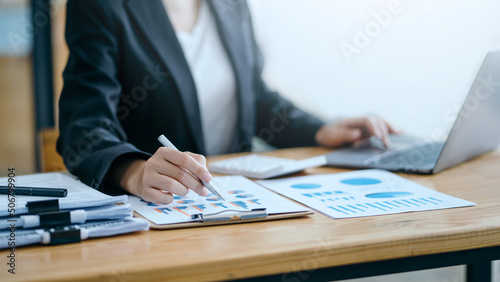Close-up of business woman hands check company finances and earnings and budget with graph on desk in the office.