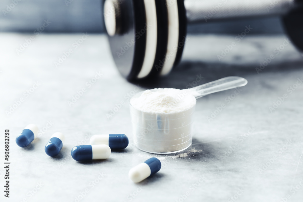 Scoop of Whey Protein and creatine capsules on stone background. Close up. Scoop of Whey Protein and creatine capsules on stone background. Close up.