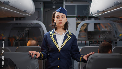Принти на полотні Portrait of woman stewardess in aviation uniform boarding people on airplane, helping with seats