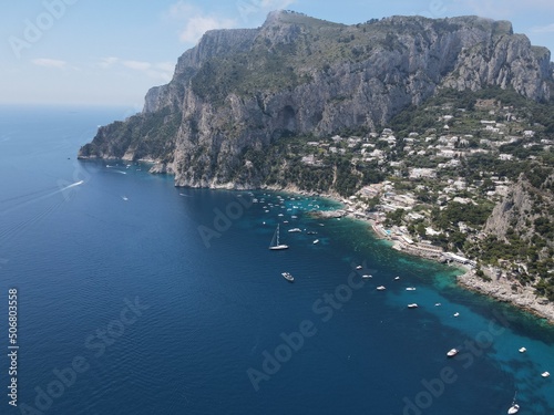 Fototapeta Naklejka Na Ścianę i Meble -  Aerial view of Capri, an island on the south side of the Gulf of Naples in the Campania region of Italy. Drone view of Faraglioni di Capri. 