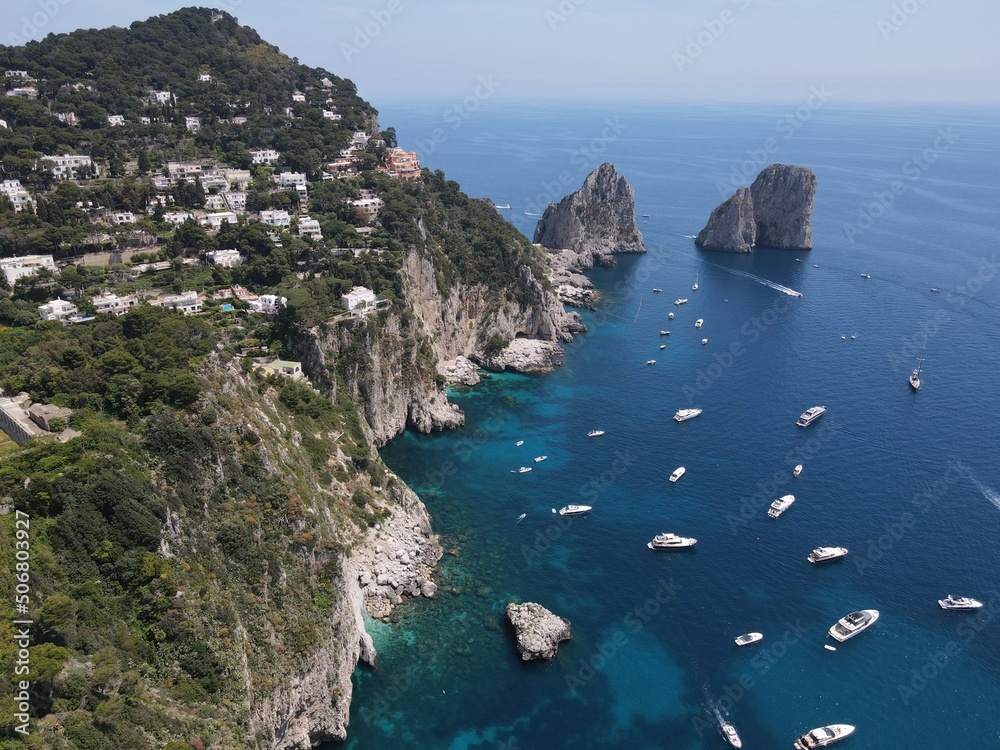 Aerial view of Capri, an island located in the Tyrrhenian Sea off the Sorrento Peninsula, on the south side of the Gulf of Naples in the Campania region of Italy. Drone view of Faraglioni di Capri.