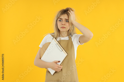 Concept of occupation, young female waiter on yellow background