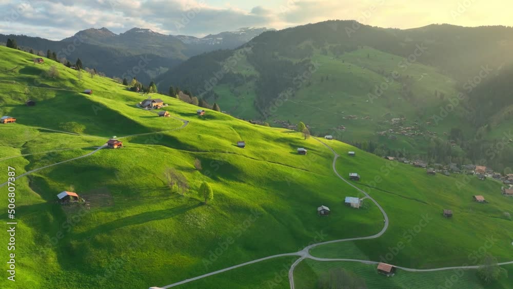 Swiss meadow with green rolling hills and mountains in the morning, idyllic rural landscape in Switzerland, aerial view of Swiss village