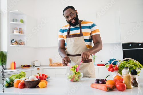 Photo of young cheerful guy prepare mix salad ingredients cuisine wear apron lunch calories dieting indoors