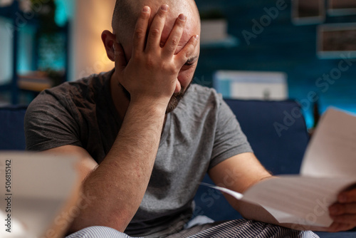 Worried person with depression reading eviction notice paper, feeling frustrated about mortgage payment and financial debt. Sad anxious man receiving bank bill warning notification. Close up. photo