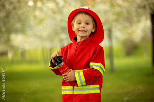 Obraz na plátně Little toddler child with fireman costume in park, pretending to be real fireman