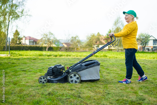 Gardener woman cuts the lawn in the garden. Worker mowing tall grass with electric or petrol lawn trimmer in city park or backyard.