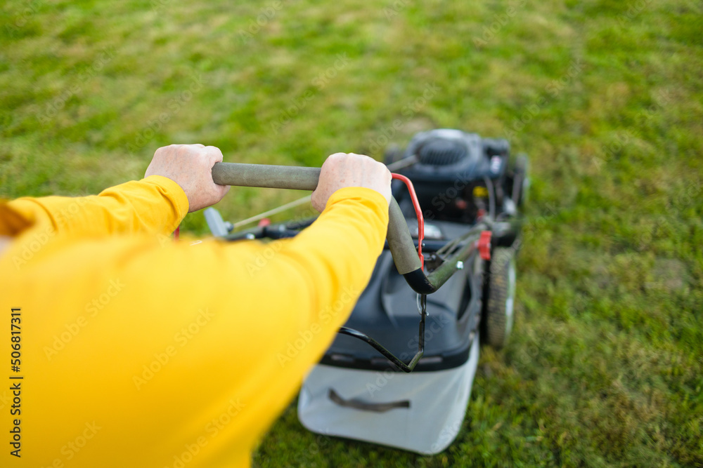 Mowing the grass with a lawn mower in early autumn. Gardener cuts the lawn in the garden. Mowing the grass with a lawn mower in early autumn. Gardener cuts the lawn in the garden.