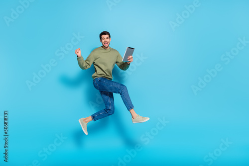 Full body photo of handsome person hold e-reader raise fist celebrate luck isolated on blue color background