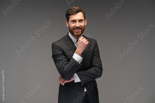 Portrait of cheerful businessman sincerely smiling at camera, having positive mood. Indoor studio shot, isolated on grey background