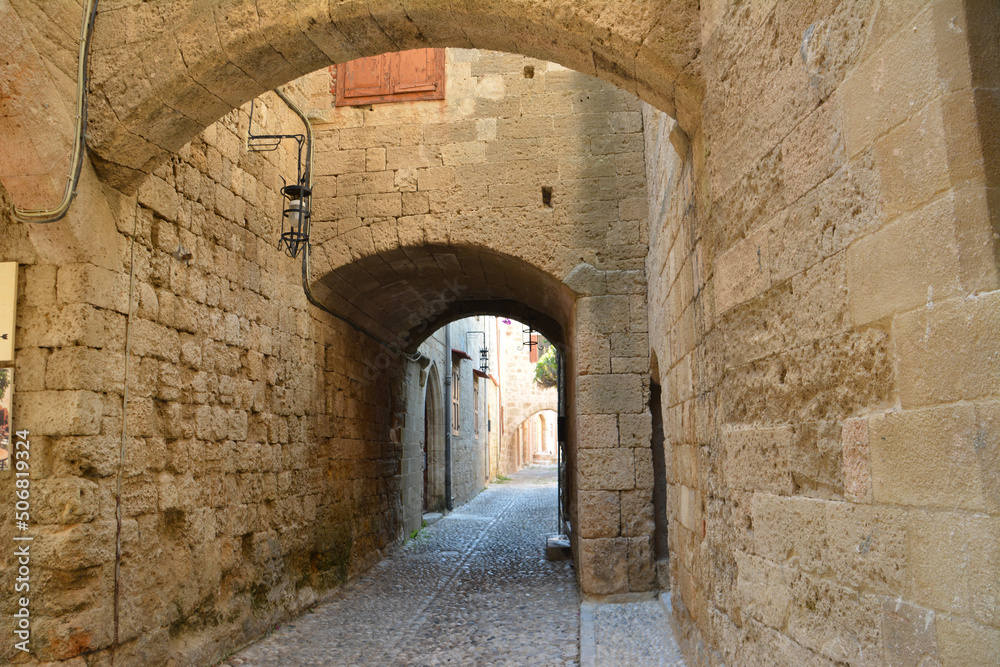 narrow medieval street with brick walls and arched entrances and stone path