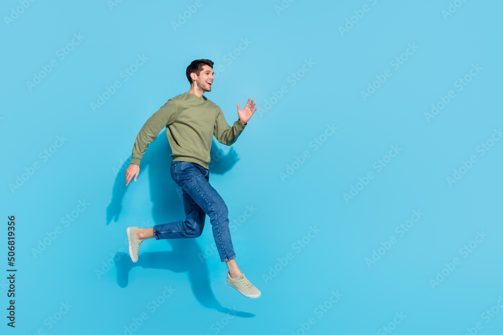 Full length photo of cute millennial brunet guy run wear shirt jeans sneakers isolated on blue background