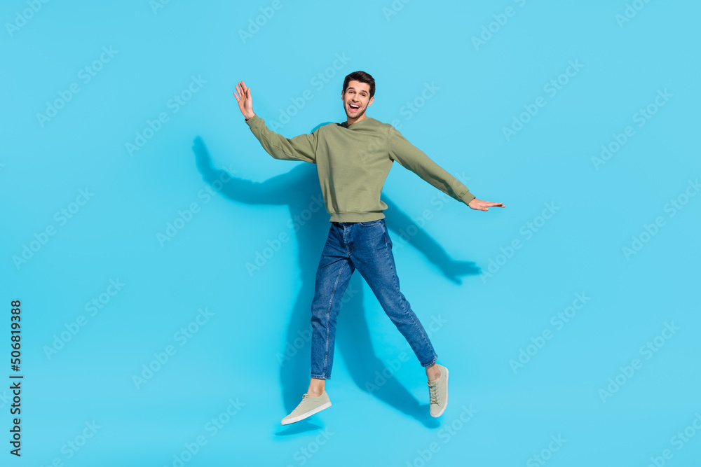 Full body portrait of satisfied glad young man enjoy free time jump isolated on blue color background