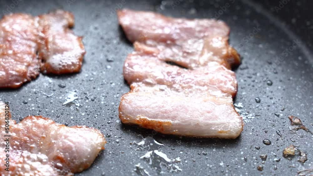Crispy pieces of delicious bacon are fried in a hot pan Crispy pieces of delicious bacon are fried in a hot pan