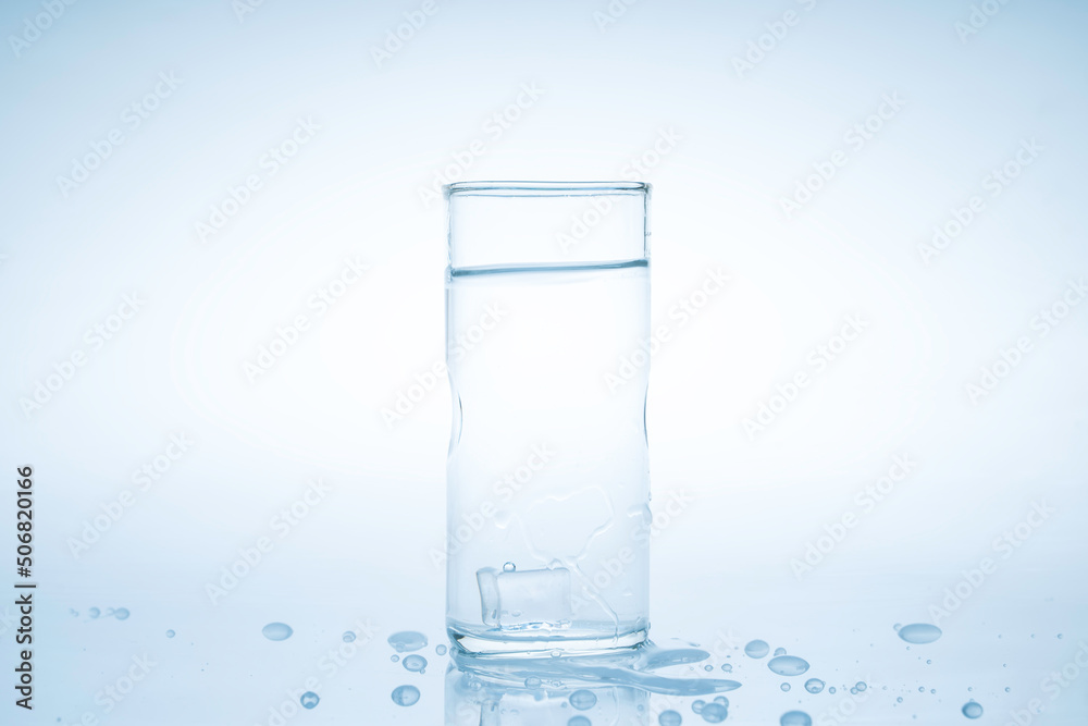 Ice cube fell into the glass of water.Water splashed from the clear glass.Fresh concept Ice cube fell into the glass of water.Water splashed from the clear glass.Fresh concept