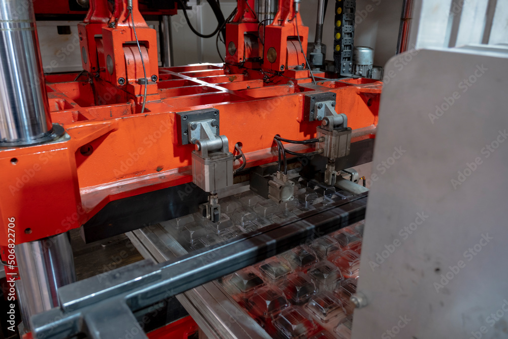 Vacuum thermoforming machine is used for producing plastic packaging in the factory. Close-up of the machine making a mold. Selective focus front Vacuum thermoforming machine is used for producing plastic packaging in the factory. Close-up of the machine making a mold. Selective focus front