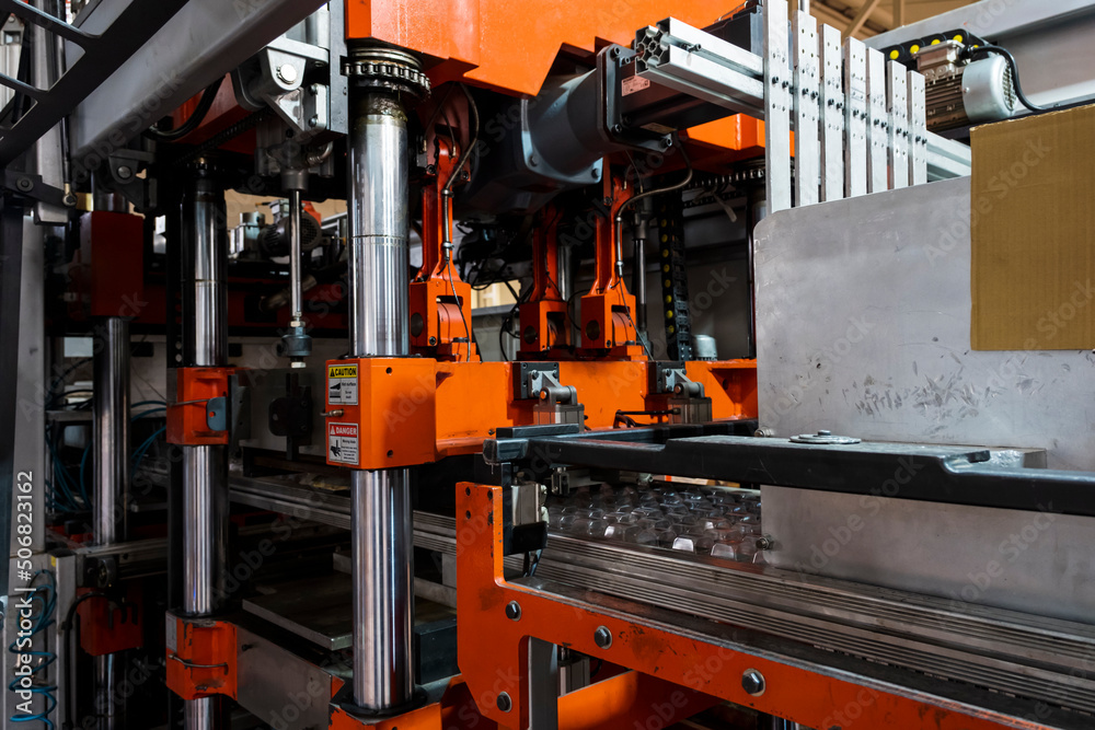 Vacuum thermoforming machine is used for producing plastic packaging in the factory. Close-up of the machine making a mold. Selective focus front Vacuum thermoforming machine is used for producing plastic packaging in the factory. Close-up of the machine making a mold. Selective focus front