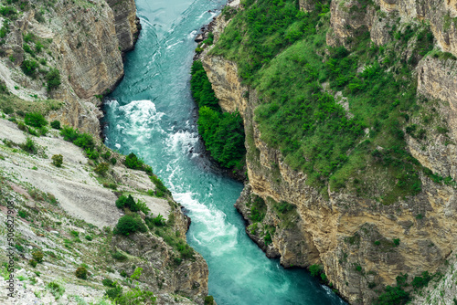 top view of a fast mountain river flowing at the bottom of a deep canyon