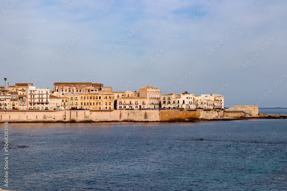 Panoramic view on the waterfront of the city of  Syracuse, Sicily, Italy, Europe EU. Soft light shining on the residential houses at the Mediterranean seaside. Walking along the coastline
