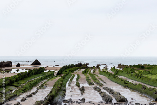 barrika beach on the basque coast in spring with the green rocks photo