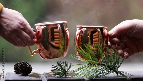 Two people drink tea in nature. Woman and man take shiny copper cups with coffee or tea and lift them. Recreation in nature concept.