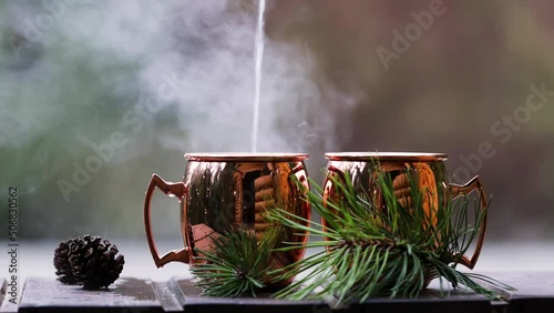 One is pouring boiling water into cups for drinking tea in nature.  Recreation in nature concept.