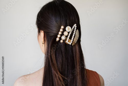 Young woman with beautiful hair clips on grey background