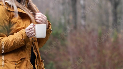 Unrecognizable  woman standing outdoors with a copper cup in her hands . Camping, recreation in nature or outdoors concept.